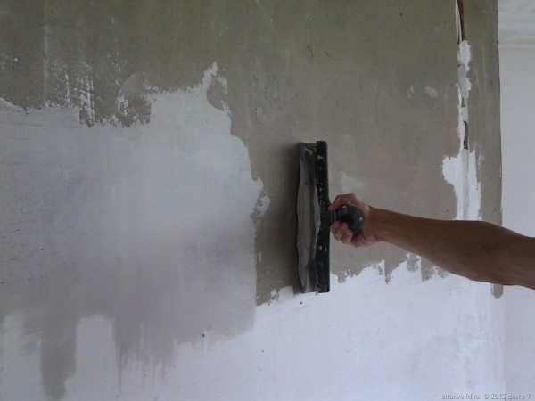 На фото- нанесение шпатлевки по бетонной стене