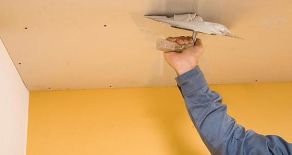 Процесс заделки швов на потолке при помощи клеевой шпатлевки.